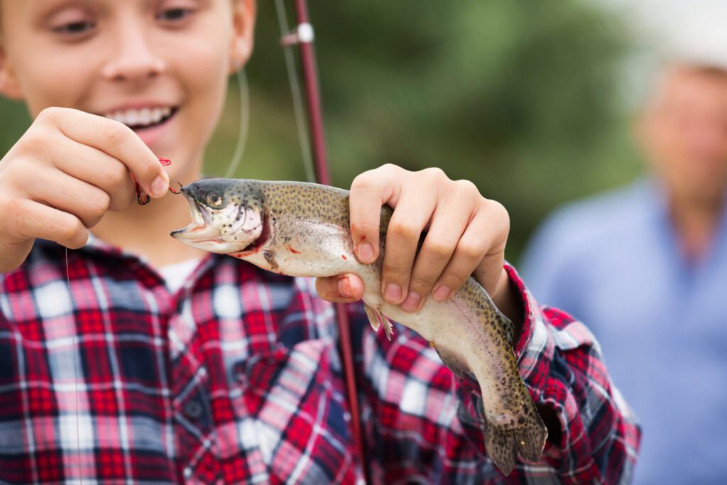 Little girl holding a trout fish.